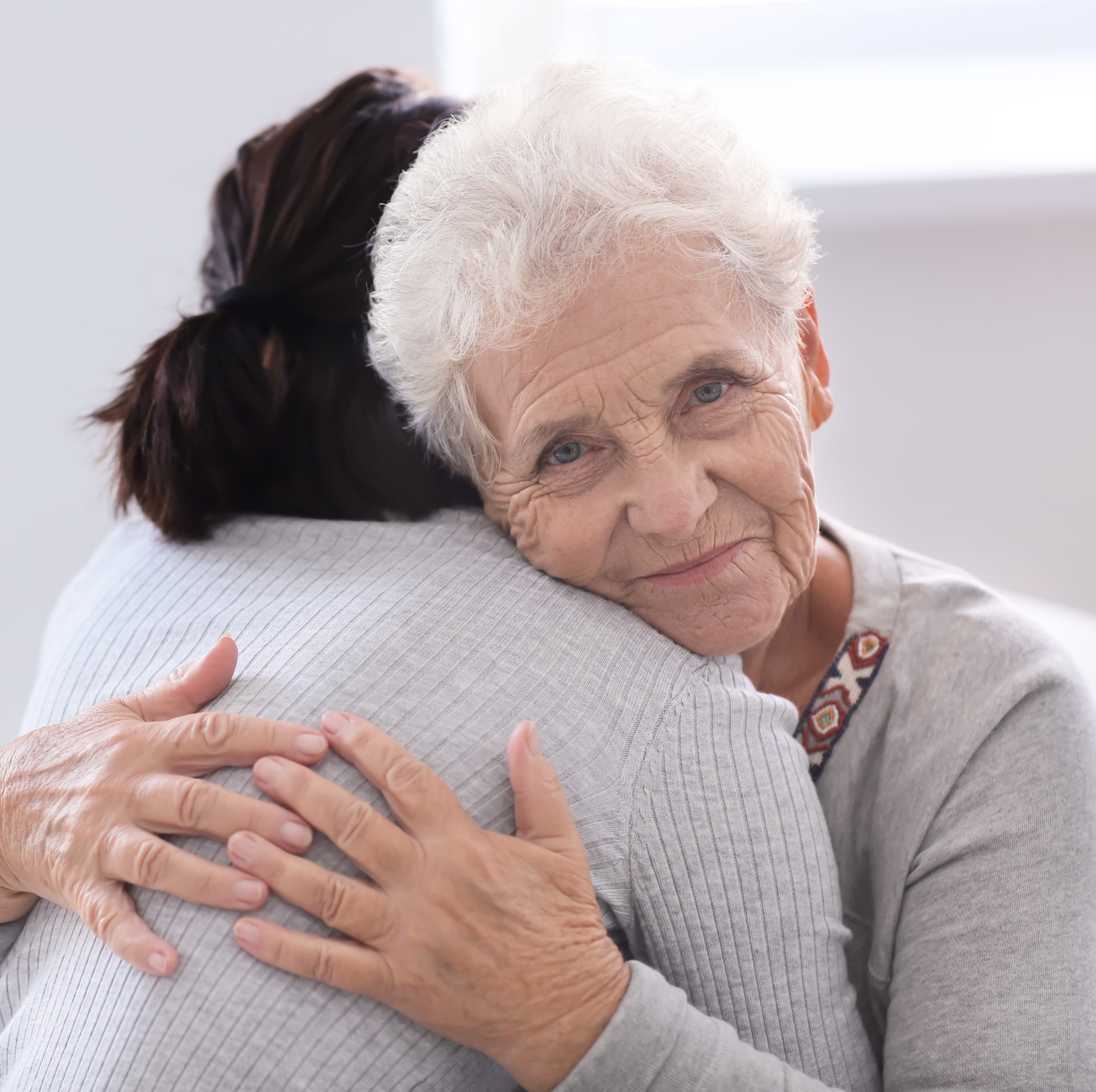 An older woman embracing her adult daughter